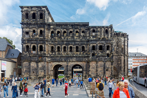 Trier, Germany - August 9th 2023: The entrance  of the back side of the Porta Nigra port city in Trier, Germany\n\nThe Porta Nigra (Latin for black gate), referred to by locals as Porta, is a large Roman city gate in Trier, Germany. It is a UNESCO World Heritage Site\nSource: Wikipedia