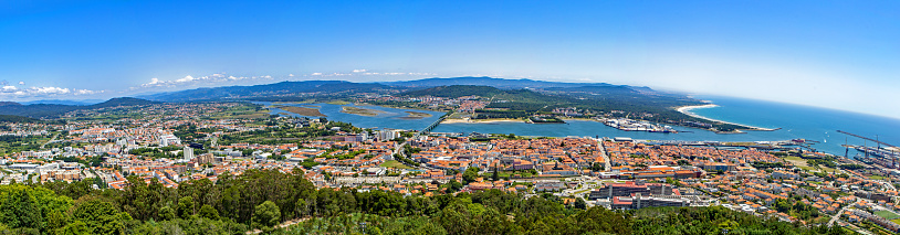 Viana do Castelo, Portugal - July 12, 2023: Panoramic bird-eye view of the city including seashore with the mountains and blue sky on the background. This is a composite photomerged extra high resolution image stitched from over a dozen full-frame single images suitable for enlarged prints or murals.