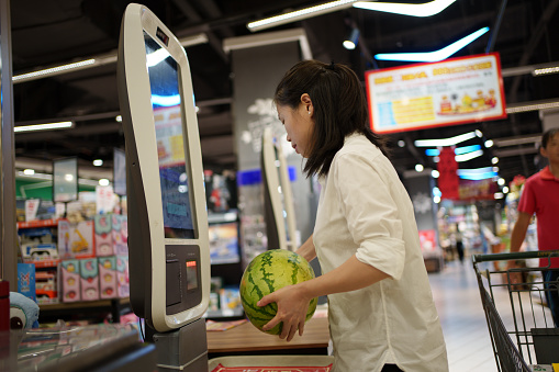 woman using self-service cash register