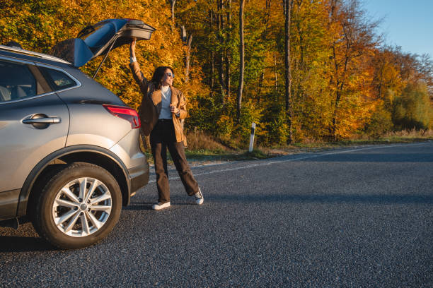 日没時に、女性が駐車中の車のトランクを閉じます - car insurance driving women ストックフォトと画像