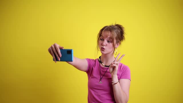 Young Woman Taking Selfies Against A Yellow Background