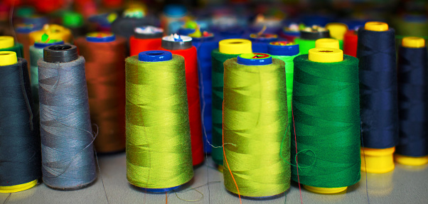 A pile of multicolored spools of sewing thread.
