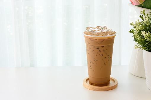 Iced espresso Thai style on a wooden plate with copy space and soft white background.