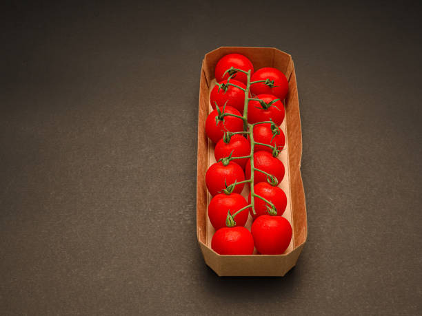 Top view of ripe red cherry tomatoes in a box over a vintage background