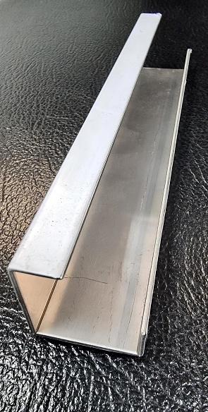 a photography of a metal strip on a black surface, lumbermill steel bar on a black surface.