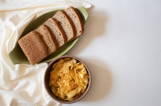 istock Brown bread slices and potato chips on a white background flat lay 1616445006