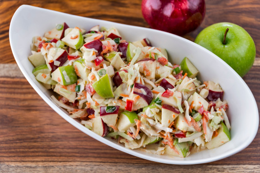 A bowl of fresh-made coleslaw with green and red apples.