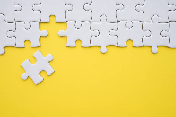 istock Unfinished white jigsaw puzzle on yellow background with copy space. 1616472278