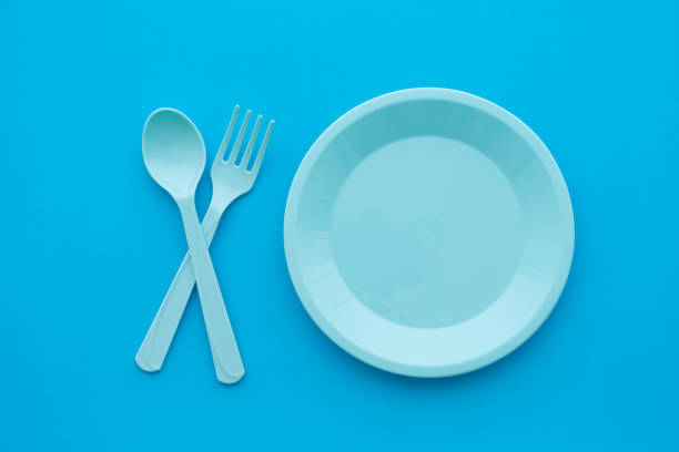 istock Flat lay of empty pastel blue dish, spoon and fork on blue background. 1616498805