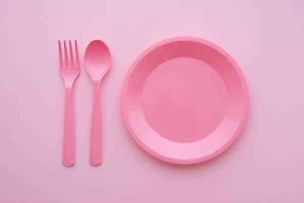 istock Flat lay of empty pastel pink dish, spoon and fork on pink background. 1616498811