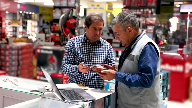 Latin American customer asking advise to a retail clerk while buying tools at a hardware store