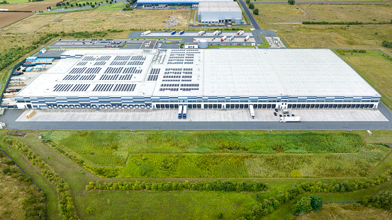 Loading bay, truck parking lot, unrecognisable industrial building, logistics - aerial view - tracking shot