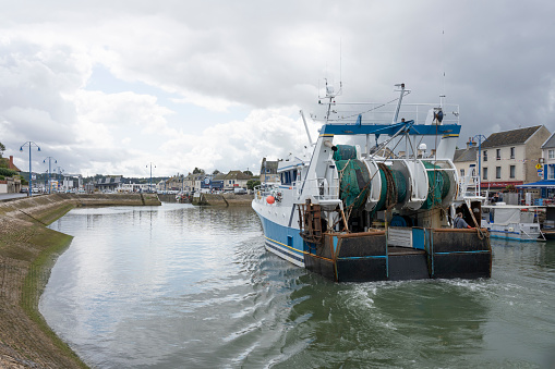 Port-en-Bessin-Huppain, France - 07 24 2023: A blue fishing boat entering the harbor
