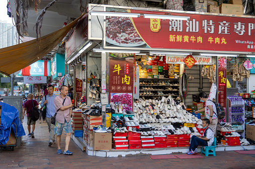 Hong Kong - August 15, 2023 : Pedestrians walk past a shoe store in Sham Shui Po, Kowloon, Hong Kong.