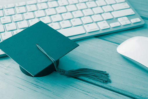 Graduation cap, keyboard with mouse computer table backgrounds. E-learning, online education concept. Monochrome tone.