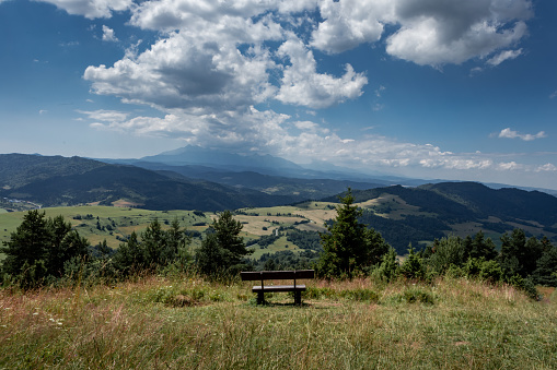 Empty wooden bench at the top of Wysoki Wierch, with a view to Pieniny Mountains, Poland. No people, sunny summer day.