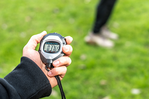 Close-up of a fitness instructor holding stopwatch outdoors