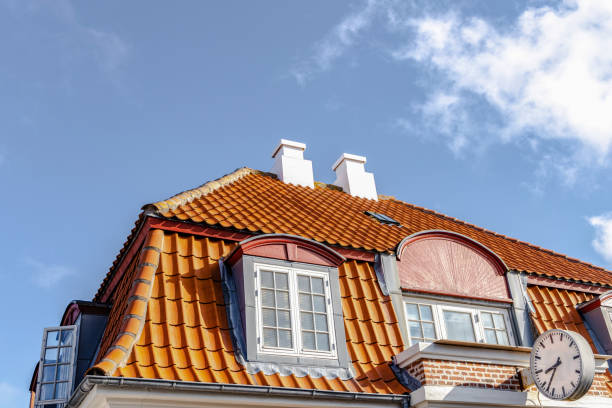 A close-up view of a classic brick roof corner, showing weathered red tiles, mortar lines, and subtle moss highlights under a bright, cloudless blue sky. The composition emphasizes texture, geometry, and the quiet charm of Danish architecture, inviting warm memories of old towns and daylight serenity.
