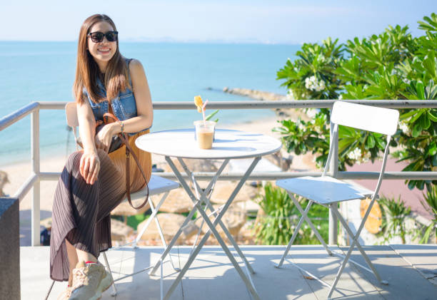 Side wide view Asian wear casual dress smile women take photo of sunrise moment vacations holidays in beautiful beach at tropical sea
