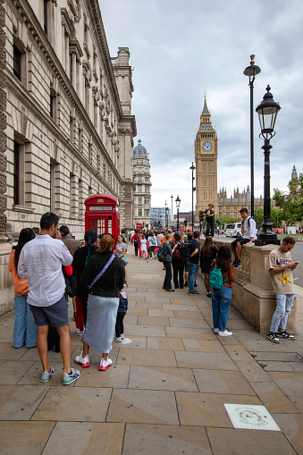 London, UK - Aug 14, 2023: A view towards Big Ben and Elizabeth Tower during the day. Red Telephone boxes and people can be seen in the foreground.