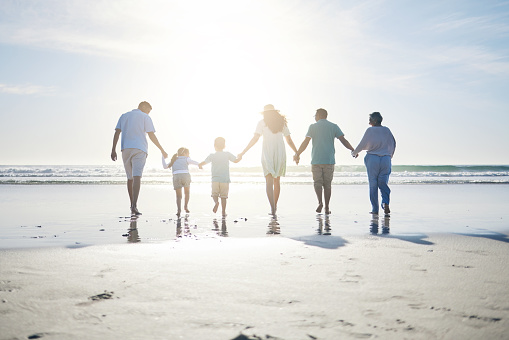 Beach, sunrise and grandparents, parents and kids by sea for bonding, quality time and relax in morning. Family, travel and mom, dad and children by ocean on holiday, vacation and adventure in nature