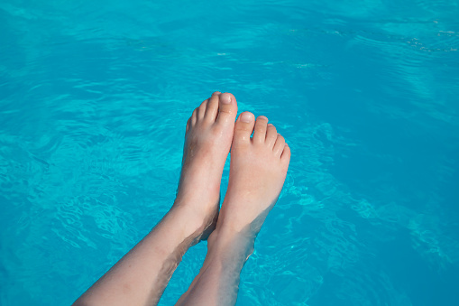 Wet feet of a 5 year old girl. The concept of children's recreation, sports and swimming in the pool.