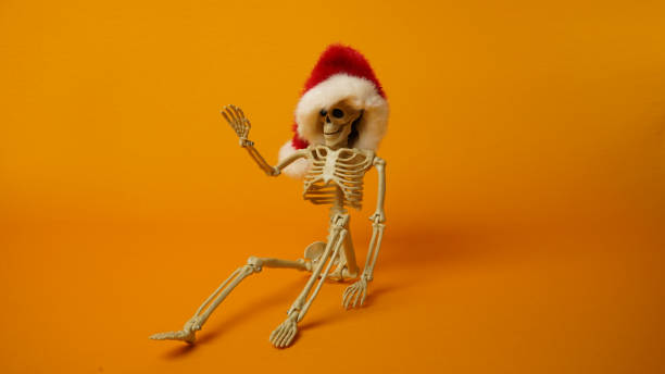 Skeletonin a Santa Claus hat on a yellow background.
