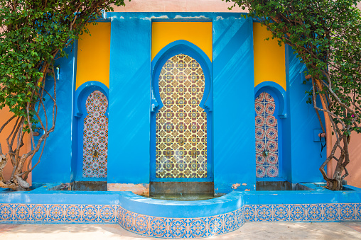 Blue flowerpot, bench and shutters on blue colorful tiles in Marrakech, detail