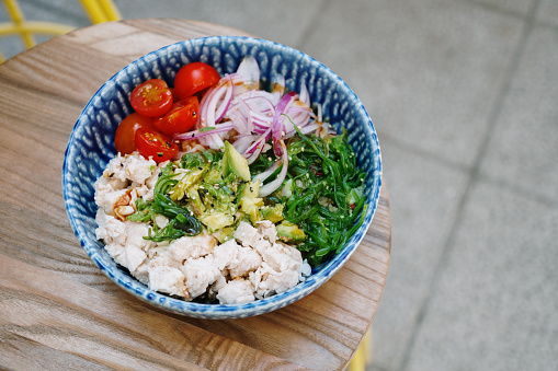 A poke bowl with chicken, cherry tomatoes, red onion, wakame and avocado
