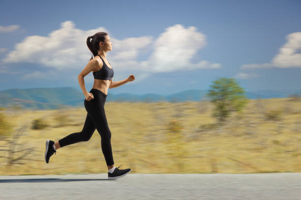 istock Young female jogging on a road 1616687614