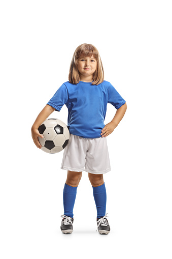 GIrl in football clothes posing with ball under arm isolated on white background