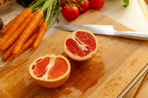 Halved red grapefruit in the kitchen - Preparing raw vegan recipes - Close up shot
