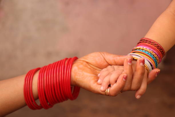 Close up of mother and daughter holding hands with colorful bracelets.
