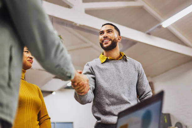 low angle view of cheerful executive shaking hands with colleague in office - iemand een hand geven stockfoto's en -beelden