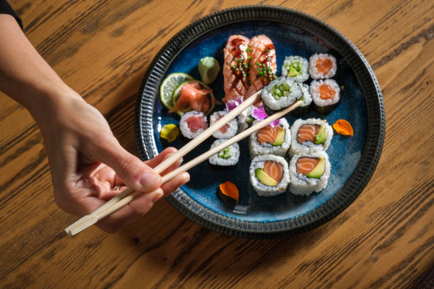 istock Person taking sushi with chopsticks from plate 1616721794