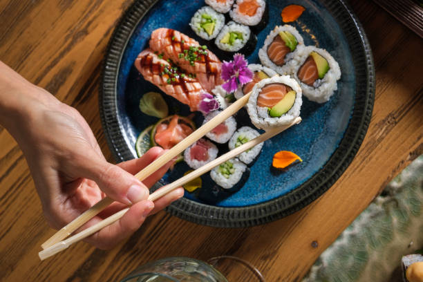 istock Person taking sushi roll with salmon and avocado 1616721815