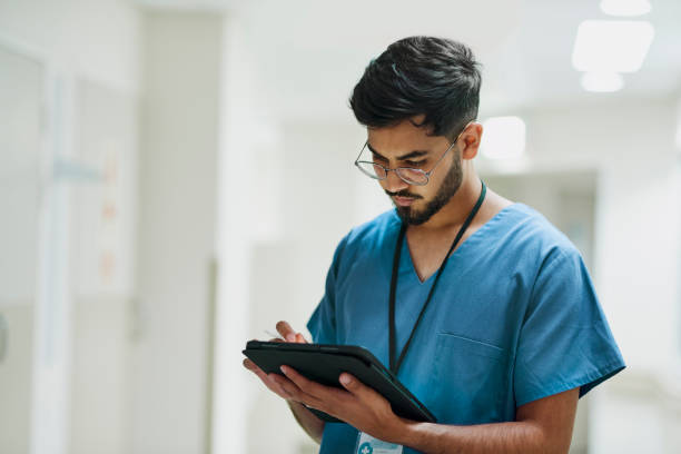 männliche krankenschwester mit digitalem tablet im krankenhaus - tablet benutzen stock-fotos und bilder