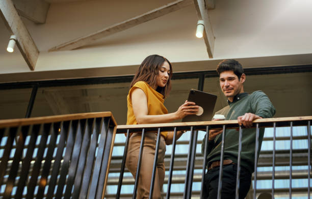 istock Low angle view of coworkers working with digital tablet beside handrails 1616722409