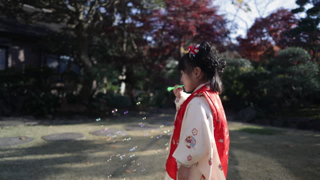 Little daughter playing with soap bubble in garden
