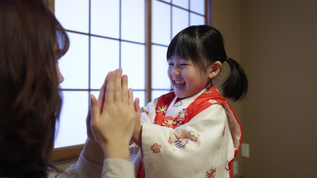 Mother and her little daughter clapping hands after wearing kimono for Shichi-go-san Japanese traditional life event