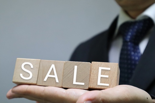 A picture of a person holding a building block that says SALE