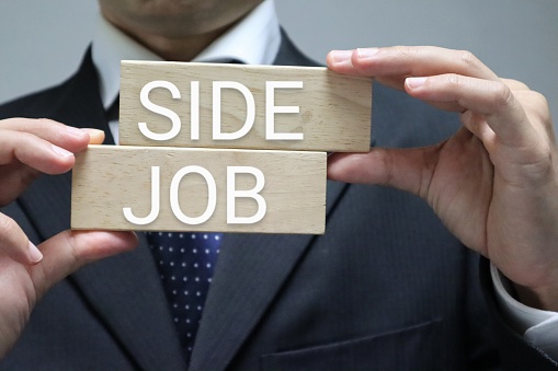 Photo of a person holding a building block that says side job