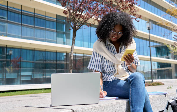 istock Happy African girl student using laptop and phone elearning in university park. 1616755996
