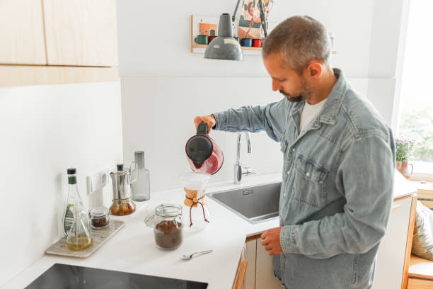 istock Young man preparing coffee using pour over coffee maker and drip kettle in the kitchen - Morning Routine before work 1616768176