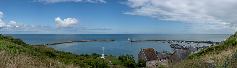 Port-en-Bessin-Huppain, France - 07 24 2023: Panoramic view of the harbor, houses and the sea from the cliffs