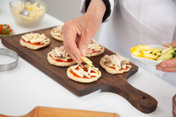 istock Adding toppings to the mini pizzas. Adding vegetables. Delicious homemade mini pizzas preparation. 1616791304