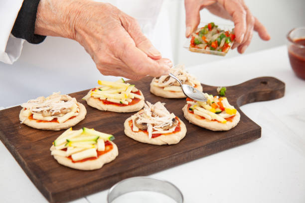 istock Adding toppings to the mini pizzas. Adding vegetables. Delicious homemade mini pizzas preparation. 1616793907