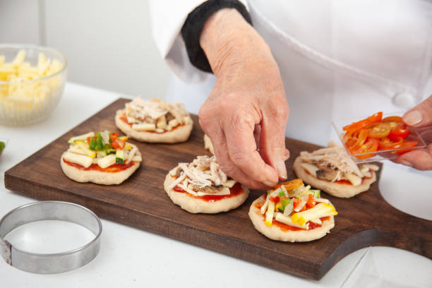 istock Adding toppings to the mini pizzas. Delicious homemade mini pizzas preparation. 1616797031