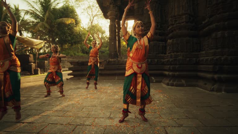 Dynamic Shot of Indian Women in Traditional Clothes Dancing Bharatanatyam in Colourful Sari While Looking at the Camera. Young Females Sharing Folk Dance and Their South Asian Culture