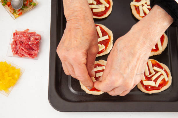 istock Adding toppings to the mini pizzas. Adding cheese. Delicious homemade mini pizzas preparation. 1616808206